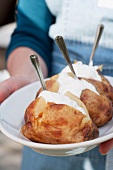 Person hält Platte mit Baked Potatoes mit Sour Cream