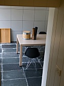 View through open doorway of table and black shell chairs on grey stone floor