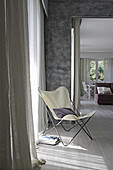 Grey accent wall and butterfly chair with cushions in modern living area