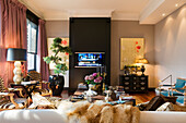 Living room with TV, patterned armchairs and flower arrangement on wooden table