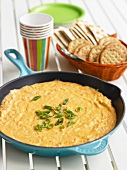 Mexican Cheese Dip in a Skillet with a Basket of Crackers