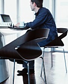 Man seated on designer chair working on laptop