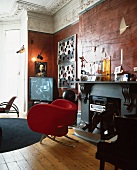 Roter Designersessel vor Kamin mit eingebauter Stereoanlage im luxuriösem Wohnraum im Barockstil