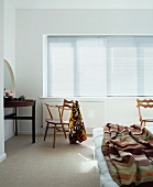 Bedroom with 50s wooden chair at dressing table in front of closed window blinds