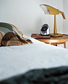 Detail of bedroom with bedside lamp and alarm clock on bedside table