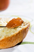 A spoonful of peach jam on a slice of brioche