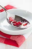 Spoon with remains of cranberry sauce in bowl on tea towel
