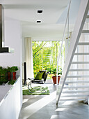 Heller Raum mit Treppe, grünem Akzentteppich und Pflanzen