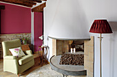 Living room with pink walls, open fireplace and light green armchair