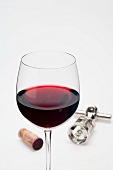 Glass of red wine, cork and corkscrew