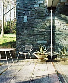 Sunny terrace corner with stone wall and metal furniture on old stone slabs