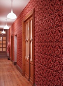 Hall with ornate wallpaper in various shades of red and artificial lighting