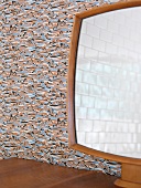 Spiegel auf Holzablage vor Wandtapete mit abstraktem Muster