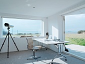 Desk in front of panoramic window in white-painted wooden house