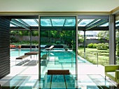 View from dining room with glass table to roofed terrace with swimming pool