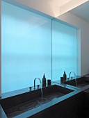 Designer sink in front of blue glass wall
