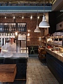 English restaurant in historic hall with brick wall, counter with decorative blue tiles and retro-style pendant lamps