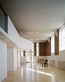 View of room with gallery, brick wall & arched windows