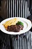 Person Holding a Plate with Skirt Steak, Spinach and French Fries