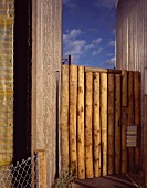 Garden gate made of wooden posts with stainless steel bell plate