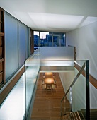 Schiebetüren vor Einbauschrank auf Galerie und Glasbrüstung um Treppenaufgang mit Blick in Wohnraum