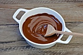 A wooden spoon in a bowl of melted chocolate