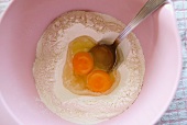 Aufgeschlagene Eier in Mehl