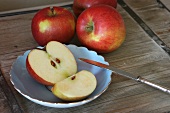 Rote Äpfel, Obstmesser, Apfelhälfte und Apfelviertel