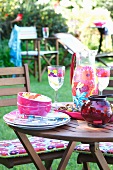 Garden table with colourful crockery, antipasti and storm lamp