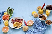 A breakfast table laid with scrambled egg, salmon, jam, muesli and grapefruit