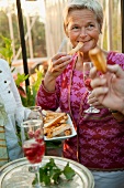 Blonde Frau isst Käsegebäck auf einer Party