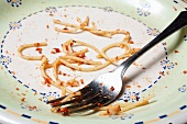 Reste von Spaghetti mit Tomatensauce auf einem Teller und einer Gabel