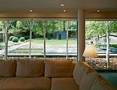Upholstered sofa in front of floor-to-ceiling terrace windows with view into modern garden