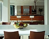 Obstkorb auf weißem Esstisch und offene Designerküche