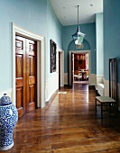 Traditional hallway painted light blue with Chinese floor vase next to wooden double doors