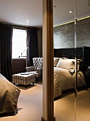 Pillar in foreground of bedroom with antique armchair and footstool