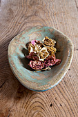 Dried roses in stone dish with worn paint on wooden surface