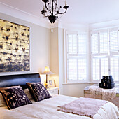 Bedroom with double bed, bedside lamp, chandelier and wall art above the bed