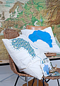 Cushions with cartographic motifs on chairs in front of large map