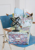 Boxes covered with cartographic motifs and stylised globe made from metal strips on vintage chair