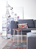 Grey sofa with floral cushion and red stool in living room