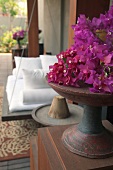 Bougainvillea flowers in wooden dish on wooden cabinet in front of spa swing bed