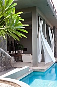 Roofed terrace with billowing curtains next to pool