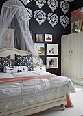 Bedroom in mixture of styles with pattern stencilled on black wall