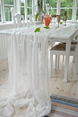 White, translucent fabric on dining table in loggia