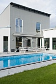 Terrasse mit Swimmingpool vor modernem Wohnhaus mit Pultdach