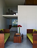 Sofa mit lindgrünen Polstern und Holzrahmengestell mit passendem Couchtisch in modernem Wohnraum mit Blick auf Galerie und in offenen Schlafraum