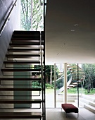Staircase with wooden treads in open-plan living room and view of exterior stairs though terrace window