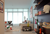 Wohnzimmerdeko mit modernen Designobjekten - elegant schwebendes Wandregal und helle Sitzgruppe im Hintergrund