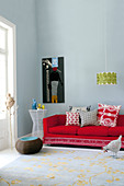 Kissen auf rotem Sofa und Hängelampe im Retrodesign in minimalistischem Wohnraum